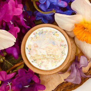 May include: A round, brown container with a white label that says "Petal Powder" in gold lettering. The label also features a floral design and the text "Rose Petals & Mineral Deodorizing Summer Velvet".
