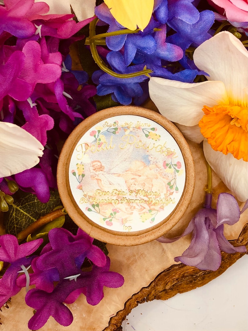 May include: A round, brown container with a white label that says "Petal Powder" in gold lettering. The label also features a floral design and the text "Rose Petals & Mineral Deodorizing Summer Velvet".