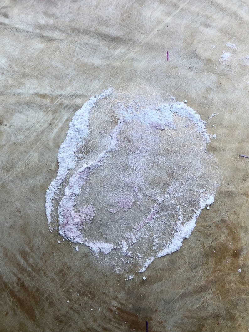 May include: A close-up of a light brown surface with a white and pink circular stain. The stain has a rough, textured surface.