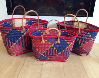 May include: Three woven baskets with red and blue geometric patterns and leather handles. The baskets are of different sizes.