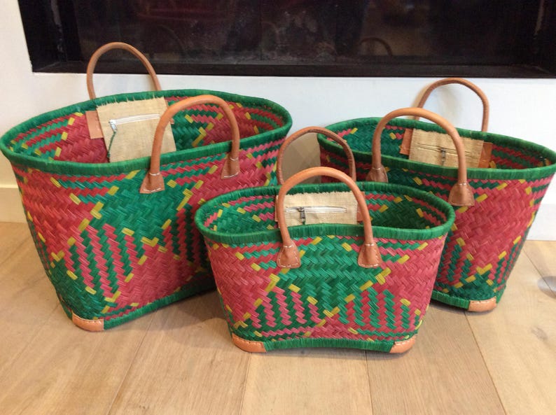 May include: Four woven baskets with leather handles. The baskets are red, green, and yellow. The baskets are different sizes.