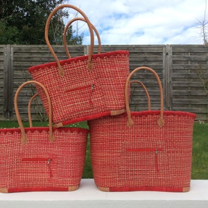 May include: Three red and white woven tote bags with leather handles. The bags are stacked on top of each other.