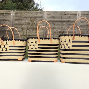 Peut inclure: Trois sacs cabas rayés noir et blanc avec des anses en cuir marron. Les sacs ont un design de drapeau breton noir et blanc avec une rangée d'arbres stylisés noirs.