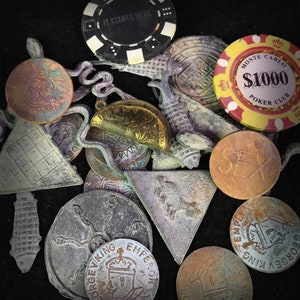 Puede incluir: Una colecci&oacute;n de fichas de metal vintage y fichas de p&oacute;quer. Las fichas presentan varios dise&ntilde;os, incluyendo un sol, una cuadr&iacute;cula, una serpiente, un rey y una ficha de p&oacute;quer que dice "It Starts Here". La ficha de p&oacute;quer es negra con puntos blancos y el texto "Monte Carlo $1000 Poker Club" est&aacute; impreso en la ficha de p&oacute;quer roja y amarilla.