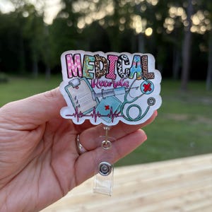 May include: A badge reel with the words "MEDICAL Records" in colorful letters. The badge features medical-themed illustrations, including a stethoscope, syringe, and a medical chart. The reel has a clear plastic strap and a metal clip.