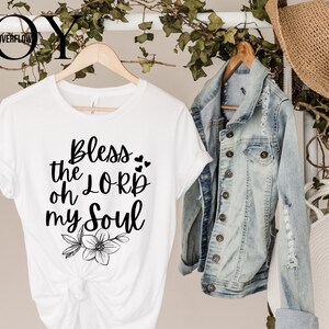 Könnte beinhalten: Weißes T-Shirt mit dem Text "Bless the Lord oh my Soul" in schwarzer Schrift und einem kleinen floralen Design unter dem Text.