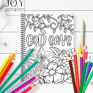 K&ouml;nnte beinhalten: Ein Schwarzwei&szlig;-Malbuch mit Spiralbindung. Der Umschlag zeigt ein florales Design mit dem Text "GOD SAYS" in einer fetten, stilisierten Schrift.