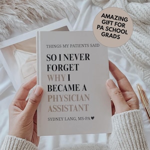 Puede incluir: Un libro blanco titulado "Things My Patients Said" con el texto "So I Never Forget Why I Became a Physician Assistant". El libro está abierto en manos. Un bolígrafo dorado descansa sobre la superficie blanca. Una pegatina circular dice "Amazing Gift for PA School Grads."