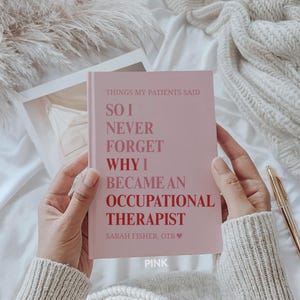 May include: A pink notebook with the text "THINGS MY PATIENTS SAID, SO I NEVER FORGET WHY I BECAME AN OCCUPATIONAL THERAPIST" is held open. The author's name, "SARAH FISHER, OTR" is below the text. The word "PINK" is at the bottom.
