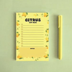 May include: A yellow notepad with the text "CITRUS GOT REAL" and a lemon pattern, next to a yellow pen. The notepad has a to-do list format with lines and circles. The background is a light green color.
