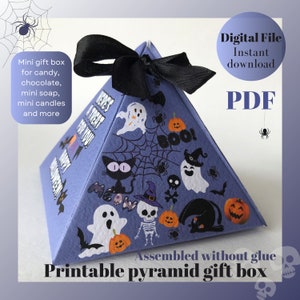 Puede incluir: Caja de regalo de pirámide imprimible con temática de Halloween con una cinta negra. La caja está decorada con fantasmas, murciélagos, arañas, calabazas y el texto "Here's a Treat for You".