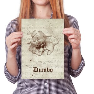 May include: A vintage-style print featuring a cartoon illustration of Dumbo the elephant, with the words "Can You Feel the Love Tonight" and "Dumbo" in a stylized font. The background is a faded sheet of music.