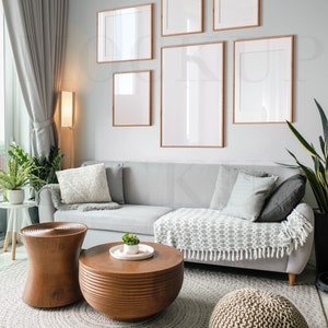 May include: A light gray sectional sofa with pillows and a throw blanket sits in a living room with a wooden coffee table and two wooden side tables. The room is decorated with framed artwork and a potted plant.
