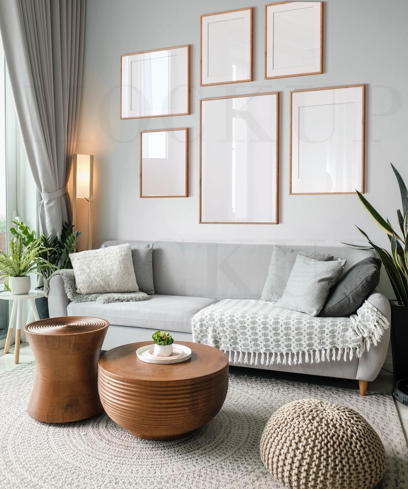 May include: A light gray sectional sofa with pillows and a throw blanket sits in a living room with a wooden coffee table and two wooden side tables. The room is decorated with framed artwork and a potted plant.