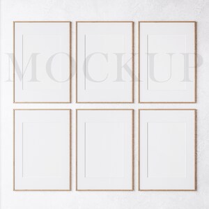 May include: Six empty picture frames with a light wood finish are arranged in two rows of three on a white textured wall. The frames are all the same size and have a simple, modern design.