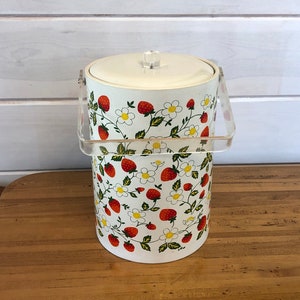May include: White plastic ice bucket with a clear plastic lid and handle. The bucket is decorated with a strawberry and flower pattern.