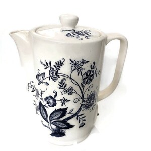 May include: White ceramic teapot with a blue floral design. The teapot has a lid and a handle.