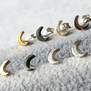 May include: A set of six crescent moon earrings in various finishes, including gold, silver, and black.