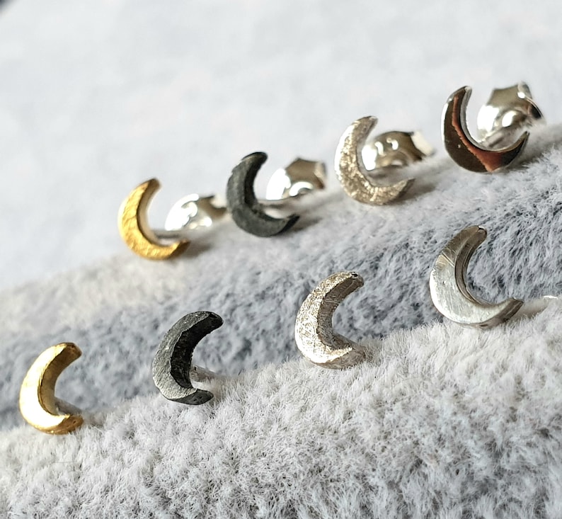 May include: A set of six crescent moon earrings in various finishes, including gold, silver, and black.