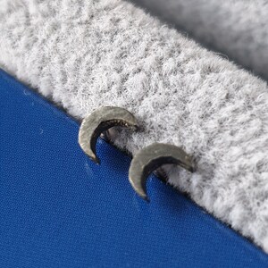 May include: A pair of silver crescent moon earrings. The earrings are small and delicate, and they have a slightly textured surface.