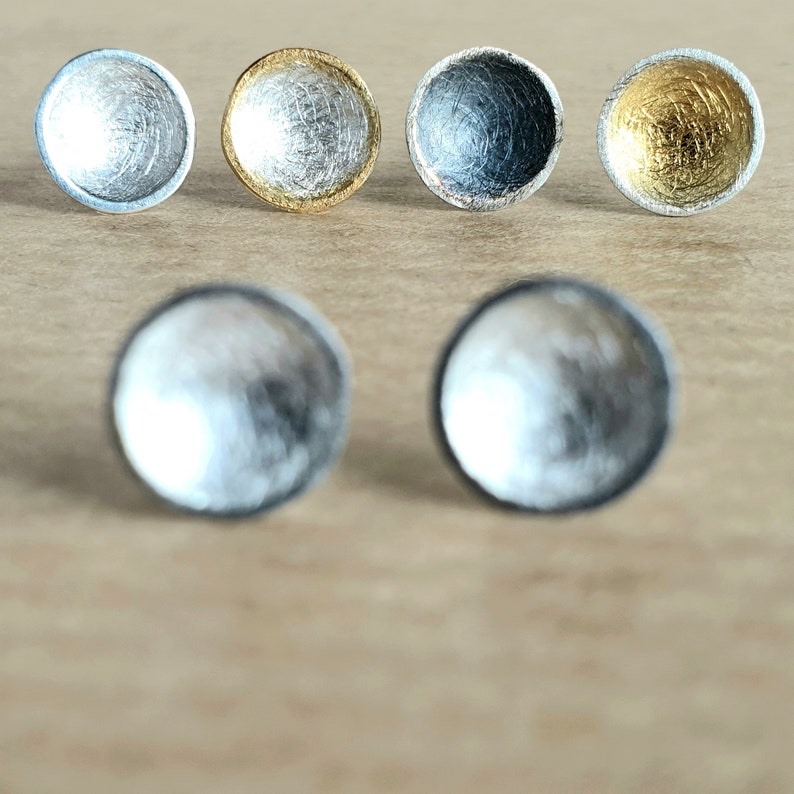 May include: Set of six silver and gold earrings. The earrings are small and round, with a textured surface. They are perfect for adding a touch of elegance to any outfit.
