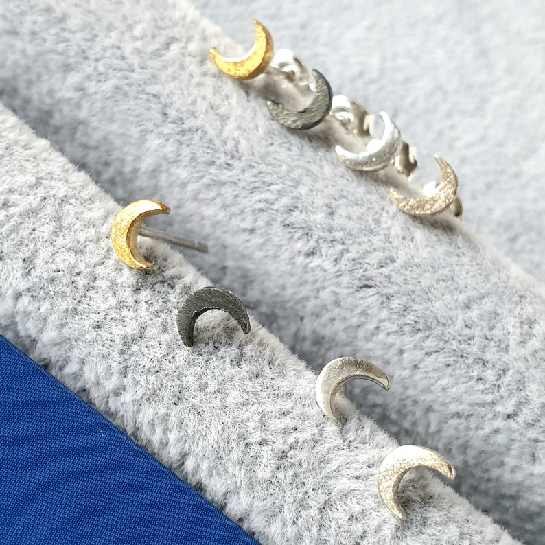 May include: A set of six crescent moon earrings in gold, silver, and black metal.
