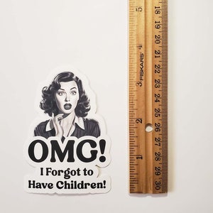 May include: A white sticker with a black and white illustration of a woman with a surprised expression. The text on the sticker reads "OMG! I Forgot to Have Children!"