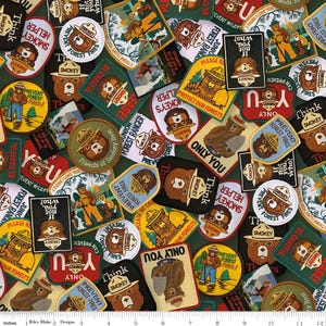 May include: A fabric pattern featuring various Smokey Bear patches in different shapes and sizes. The patches display Smokey Bear illustrations, text like "Prevent Forest Fires," and "Only You," in a mix of colors including green, red, yellow, and brown.