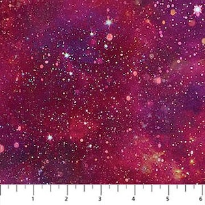 May include: A close-up of a fabric with a galaxy design. The fabric features a deep red and purple color scheme with white and yellow star-like specks. The fabric is measured with a ruler in inches.