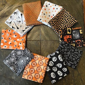 May include: A collection of Halloween-themed fabric squares in various patterns and colors. Designs include witch hats, brooms, candy corn, jack-o'-lanterns, spiderwebs, and geometric shapes. The color palette features orange, black, white, and cream.