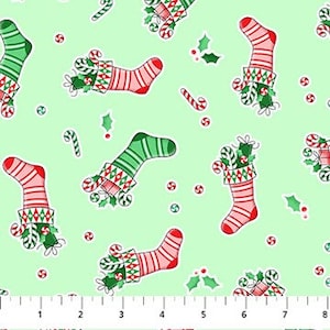 May include: A light green fabric with a repeating pattern of Christmas stockings, candy canes, and holly. The stockings are red and green with white accents and are filled with candy canes and holly. The candy canes are red and white.