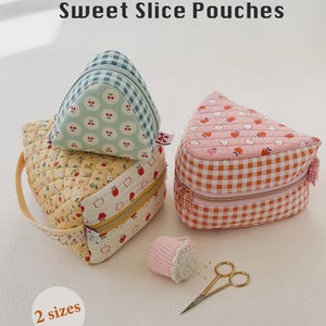 May include: Three triangular fabric pouches labeled Sweet Slice Pouches, featuring quilted patterns in yellow, pink, and blue gingham with apple and cherry prints. Includes a small pink pincushion and gold embroidery scissors on the surface.