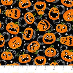 May include: Halloween-themed fabric featuring orange jack-o'-lanterns with various expressions on a black background. White swirls and small white stars are scattered throughout the design. A ruler is at the bottom.