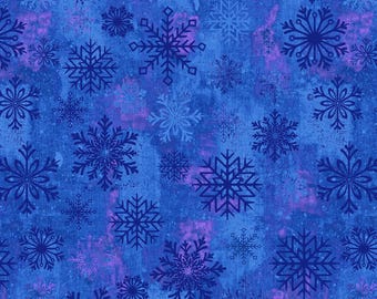 Op de afbeelding: Een stofpatroon met een herhalend ontwerp van sneeuwvlokken in verschillende tinten blauw en paars tegen een getextureerde blauwe achtergrond. De sneeuwvlokken hebben gedetailleerde patronen, wat een winterthema creëert.
