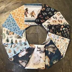 May include: A collection of twelve fabric swatches arranged in a circle, featuring various patterns including Bigfoot figures, forest landscapes with trees and mountains, colorful autumn leaves, and scattered footprints on dark and light backgrounds.