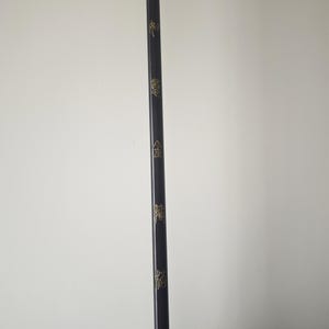 May include: A black wooden stick with gold lettering. The lettering reads "金", "龍", "鳳", and "龍".