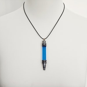 May include: A black cord necklace with a silver pendant shaped like a vial filled with blue liquid.