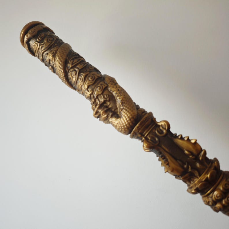 May include: A gold-colored decorative walking stick with intricate carvings of dragons and clouds.