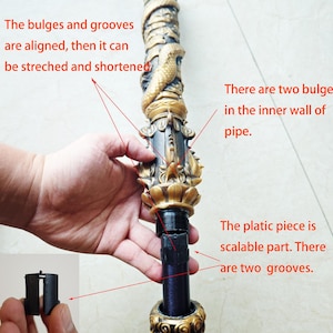 May include: A close-up of a telescopic staff with a gold and black decorative top. The staff is made of metal and has a black plastic piece that can be adjusted to change the length of the staff. The text "The bulges and grooves are aligned, then it can be stretched and shortened" is visible in the image. The text "There are two bulges in the inner wall of pipe." is also visible in the image. The text "The platic piece is scalable part. There are two grooves." is also visible in the image.
