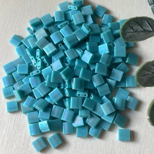 Könnte beinhalten: Ein Haufen hellblauer quadratischer Glasperlen mit einem dezenten irisierenden Schimmer.