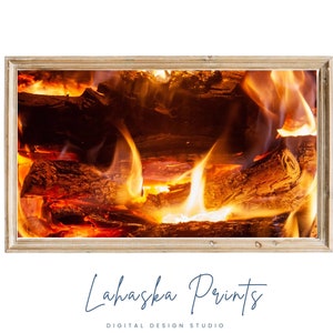 May include: A framed photograph of a fireplace with burning logs and flames. The flames are orange and yellow, and the logs are glowing red. The frame is made of wood and has a light brown finish.
