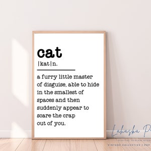 Peut inclure: Une affiche encadrée avec la définition du mot "chat" en texte noir sur fond blanc. La définition décrit la capacité d'un chat à se cacher et à effrayer. L'affiche est dans un cadre en bois clair et comprend le texte "Lahaska Prints".