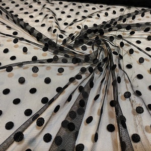 Peut inclure: Tissu noir transparent avec de grands pois noirs. Le tissu est doux et a un léger brillant.