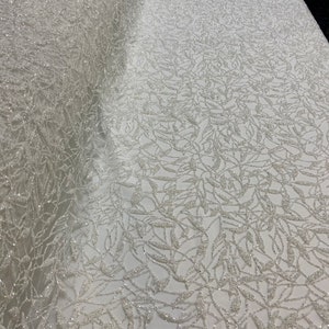 Tulle ivoire pailleté platine en relief. Tissu de mariée en tulle blanc cassé brillant. Robe de mariée, bal de promo, soirée, robe de remise des diplômes.