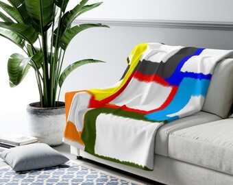 May include: A white throw blanket with a colorful abstract design featuring squares in shades of yellow, orange, red, green, blue, and black.
