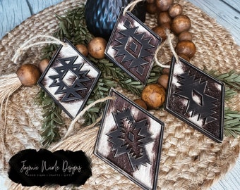 May include: Four diamond-shaped ornaments with a brown and white geometric pattern. The ornaments have a tassel and are hanging from a twine string. The ornaments are on a woven brown background.
