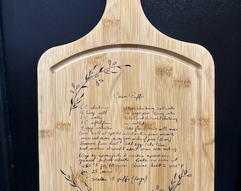May include: A wooden cutting board with a recipe for Cream Puffs engraved on it. The recipe includes ingredients like shortening, salt, water, flour, eggs, and sugar. The board is decorated with a floral design.