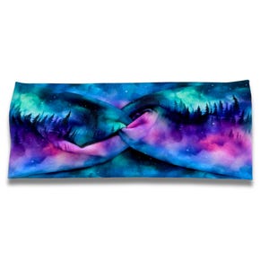 May include: A fabric headband featuring a twisted front design with a printed pattern of a dark forest silhouette against a vibrant night sky filled with swirling shades of blue, purple, and teal, resembling the aurora borealis in the night.
