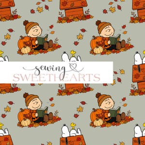 May include: A repeating pattern on a light grey background featuring Charlie Brown wearing an orange beanie and scarf, reading a book while sitting among pumpkins and autumn leaves, with Snoopy and Woodstock atop a doghouse. Text reads sewing SWEETHEARTS.