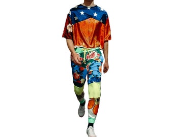 May include: A person wearing a red, white, and blue patterned shirt with a floral print on the pants. The person is wearing a pink and white hat.